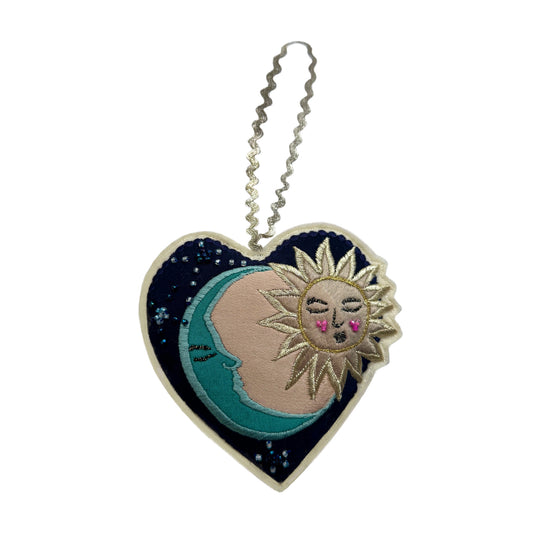 Heart-shaped decoration with sun and moon design on a white background