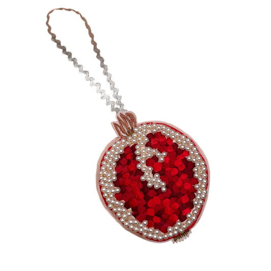 Red pomegranate decoration with white beads on a white background