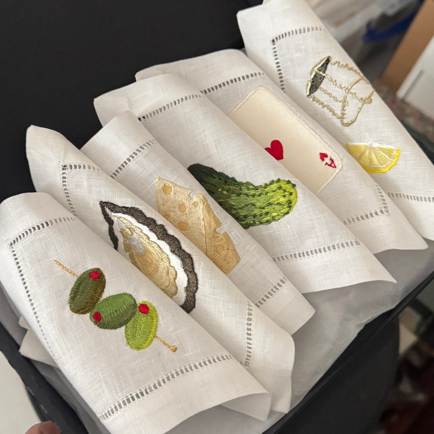 Set of embroidered napkins with various designs in a black box