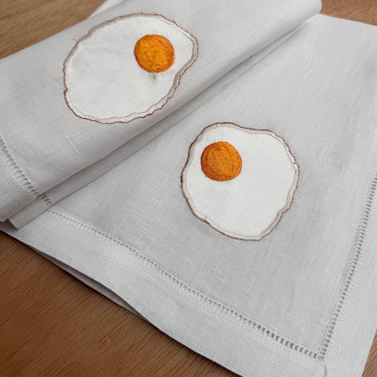 Pair of fried egg napkins on wooden table