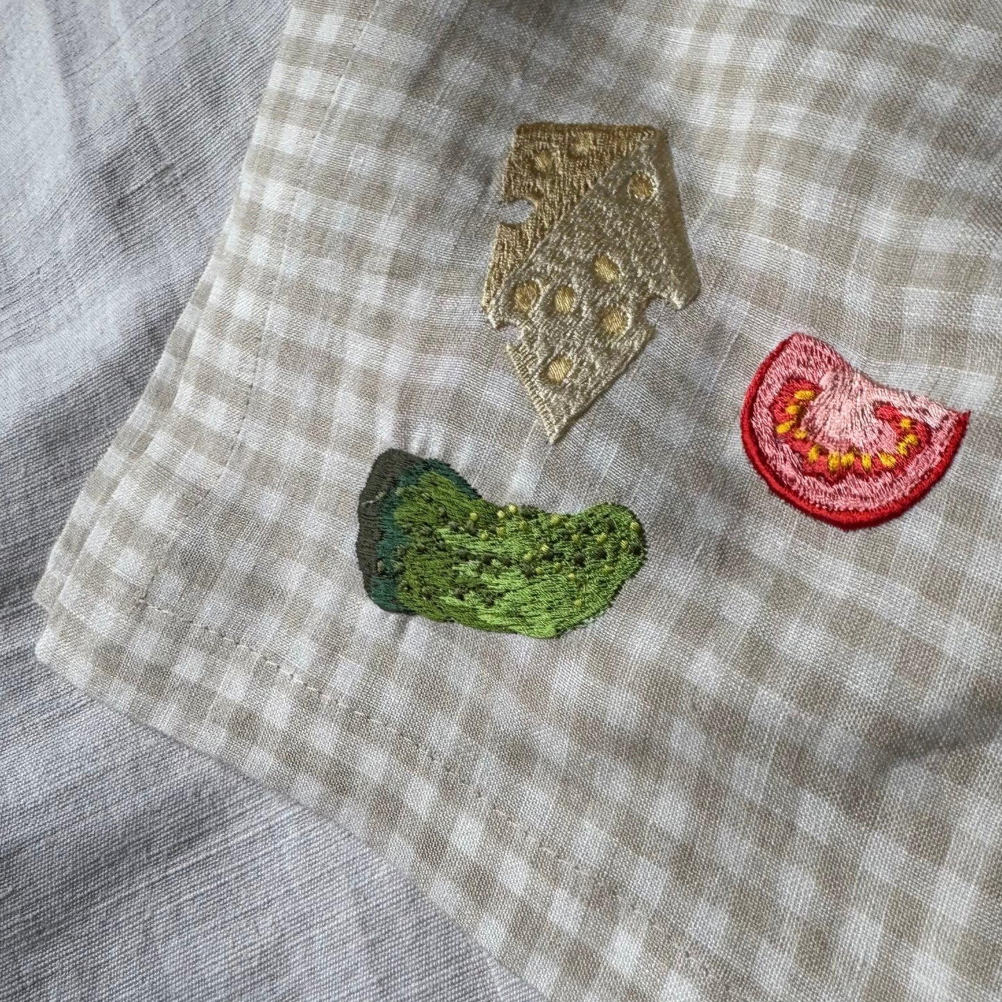 Cheese, gherkin and tomato slice embroidery on gingham napkin