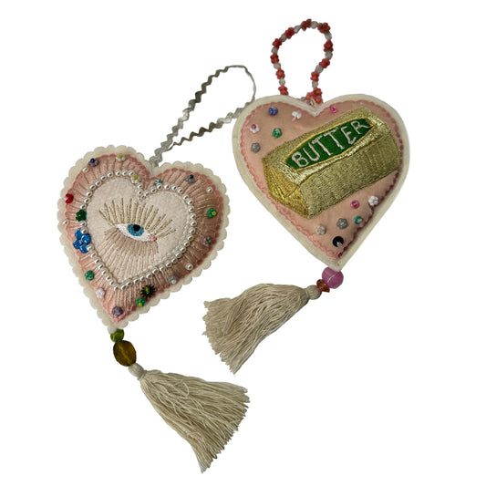 Two heart-shaped decorative items with tassels on a white background