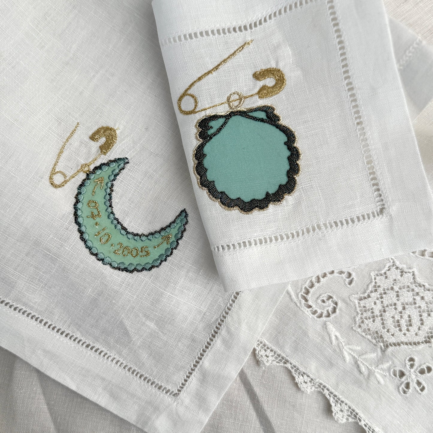 Embroidered coasters with decorative moon and shell charms with embroidered text on a white background