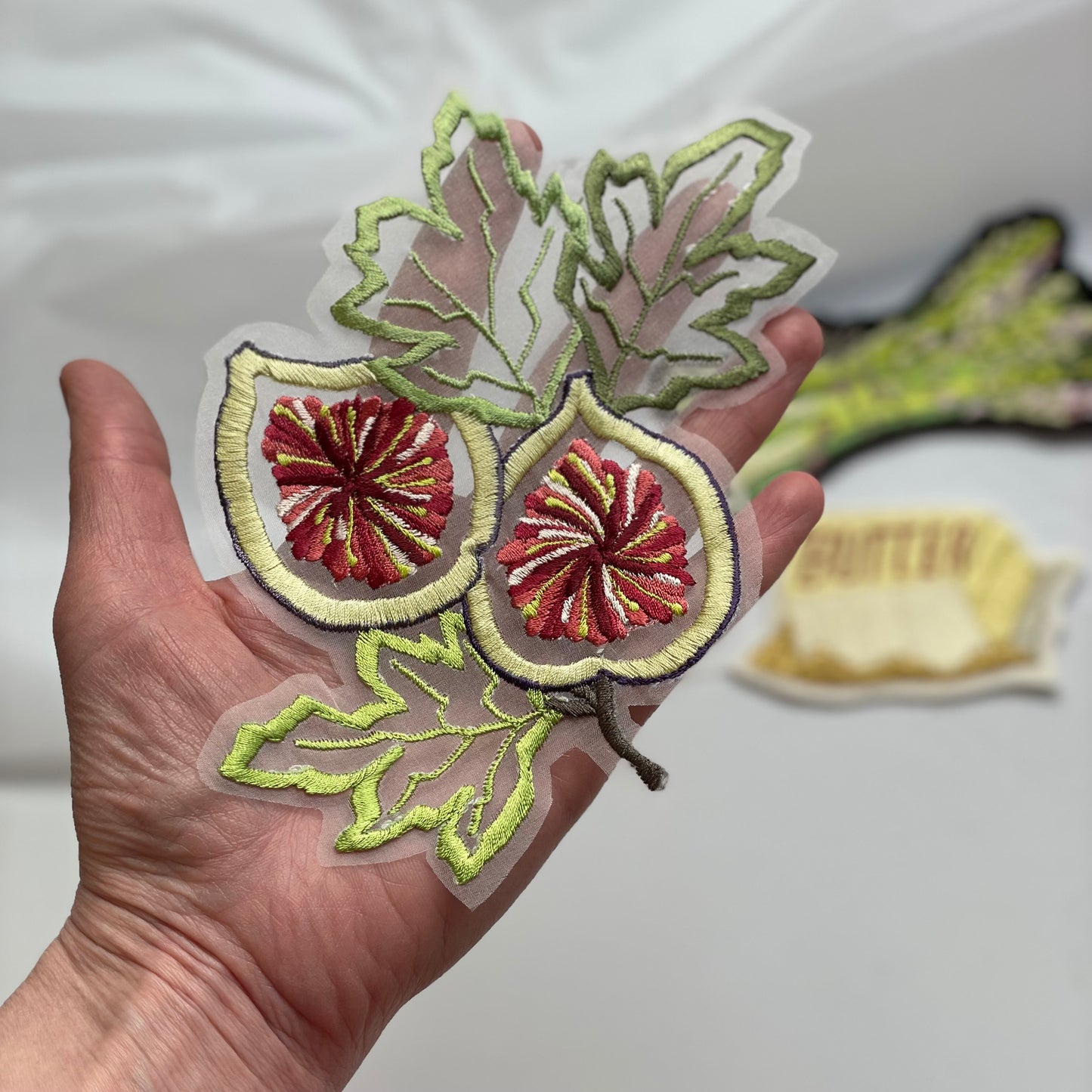 Sheet silk fig embroidery in hand for scale