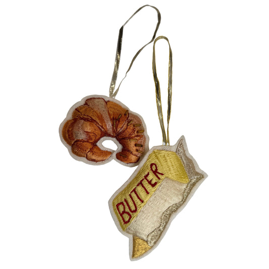 Decorative ornament shaped like a croissant and a block of butter on a white background