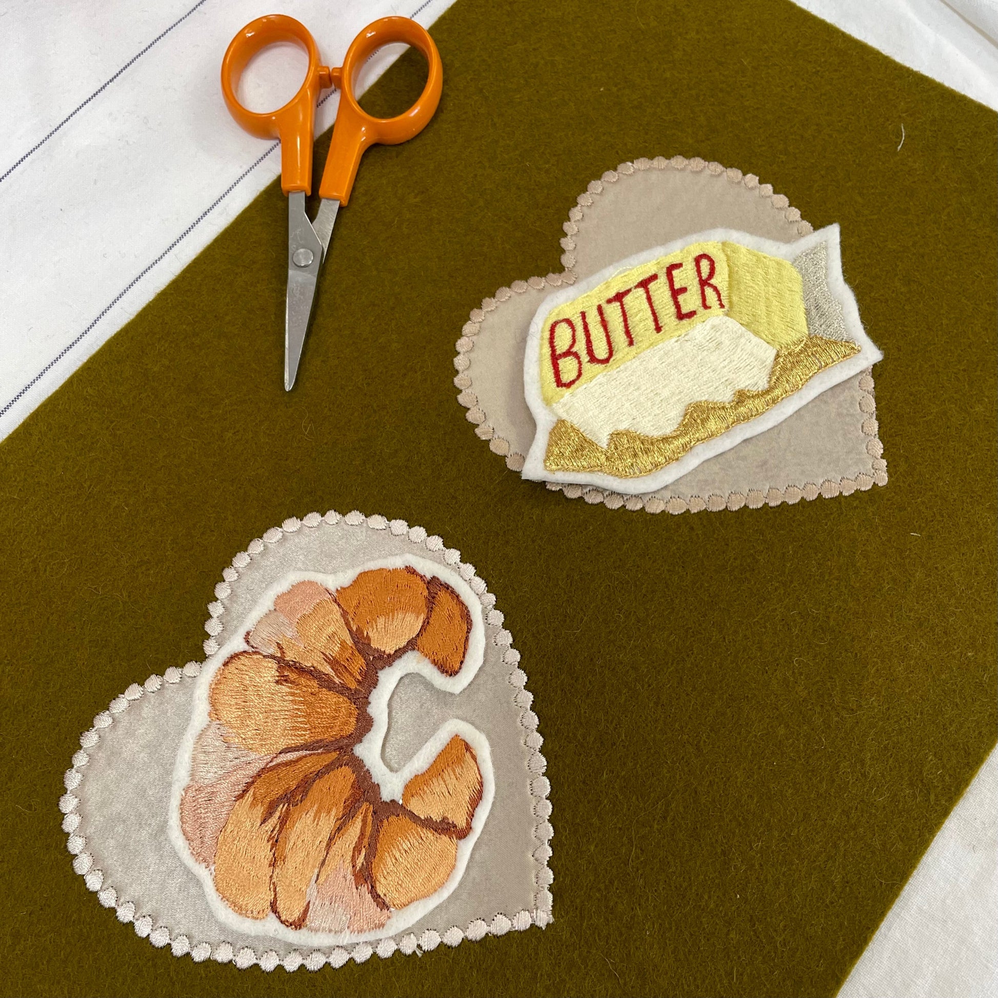 Croissant embroidered patch and butter embroidered patch on khaki felt background