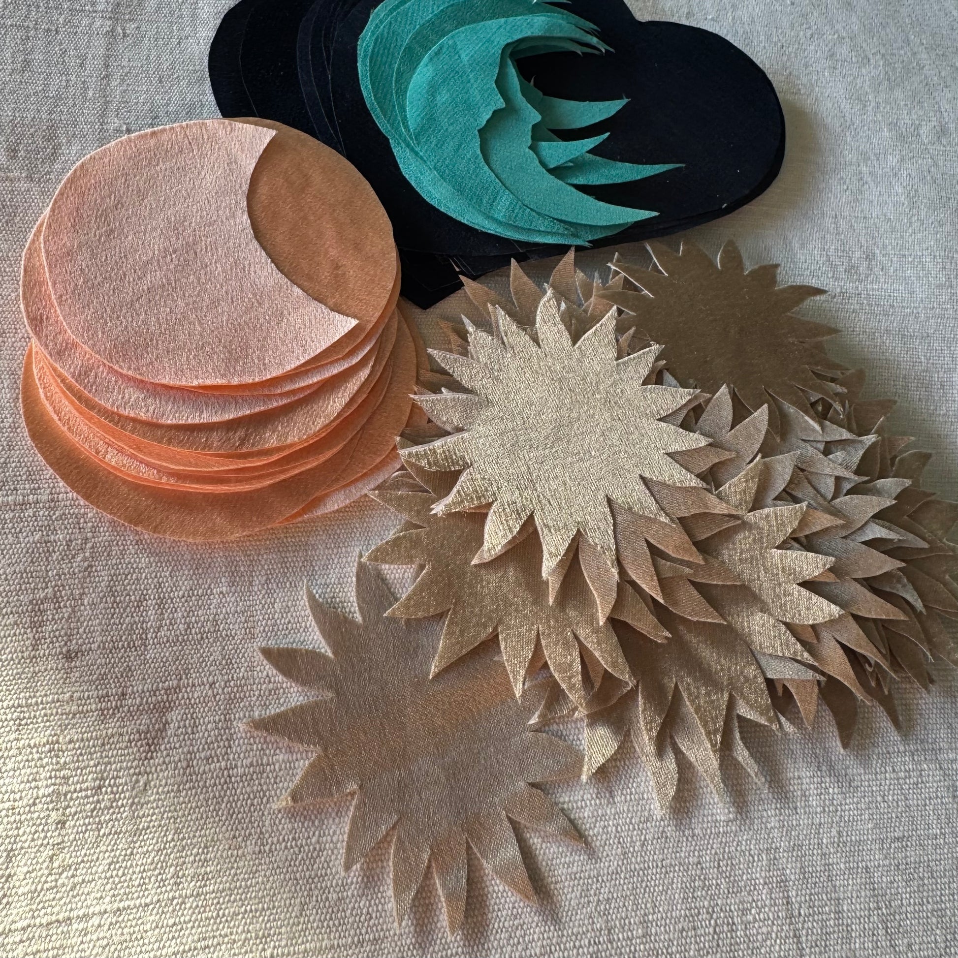 Stacks of cut silk shapes for the appliqué of the patches on a white cloth