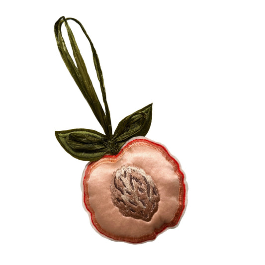 Decorative peach ornament with a green stem on a white background