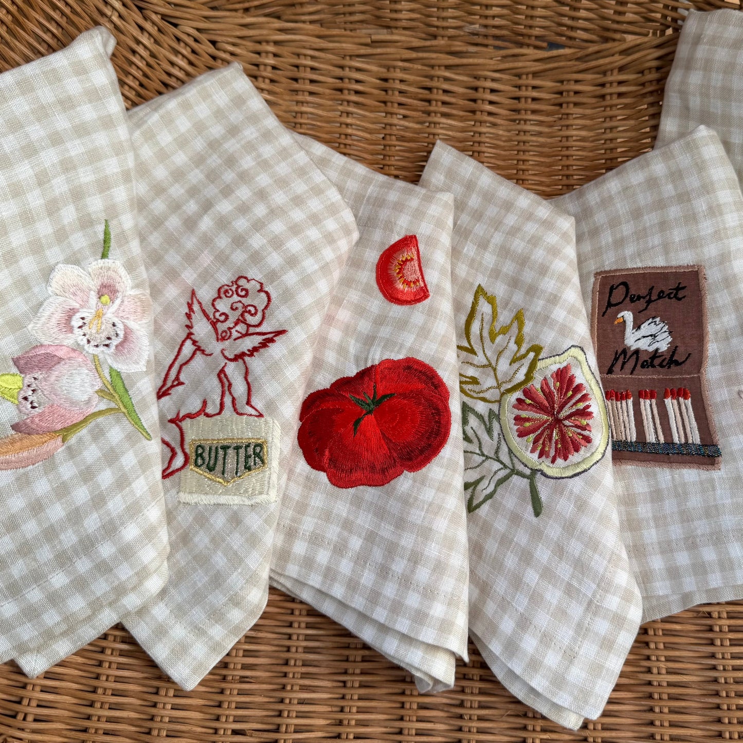 Set of embroidered napkins with various designs on a woven surface