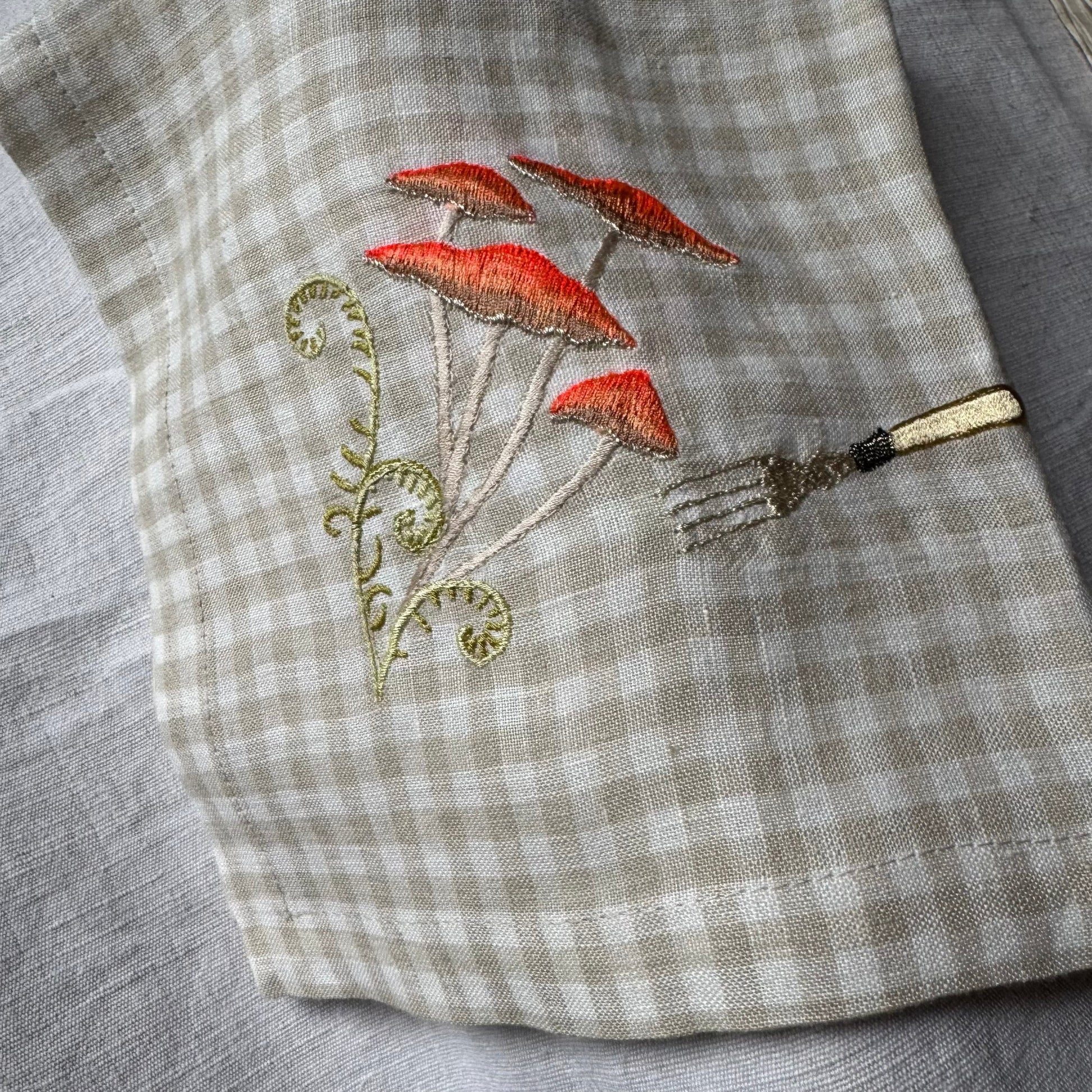 Embroidered orange mushrooms and fork on gingham napkin