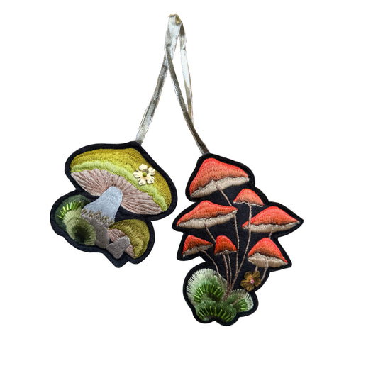 Two embroidered mushroom designs on a white background