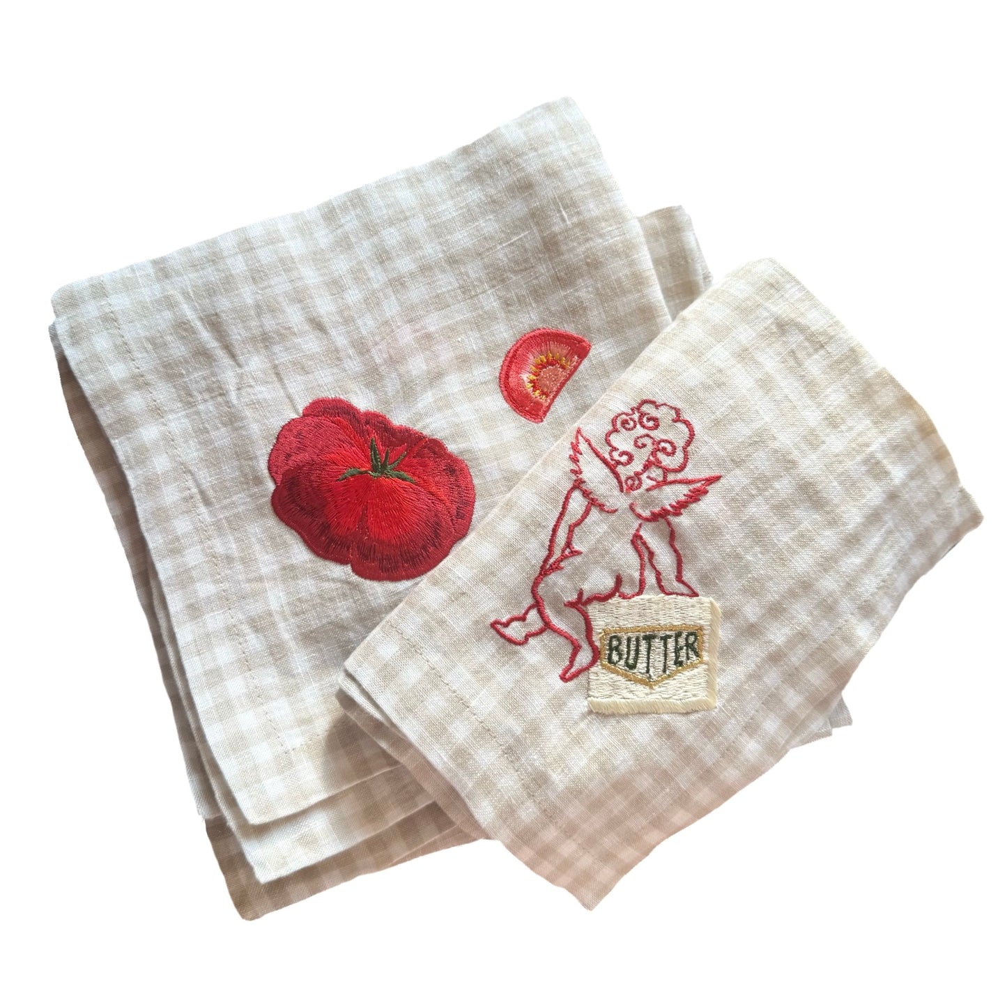 Two embroidered napkins with tomato and butter design on a white background