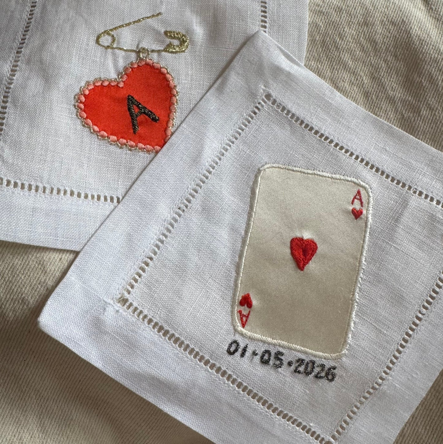 Two embroidered coasters with love heart designs and text on a beige background