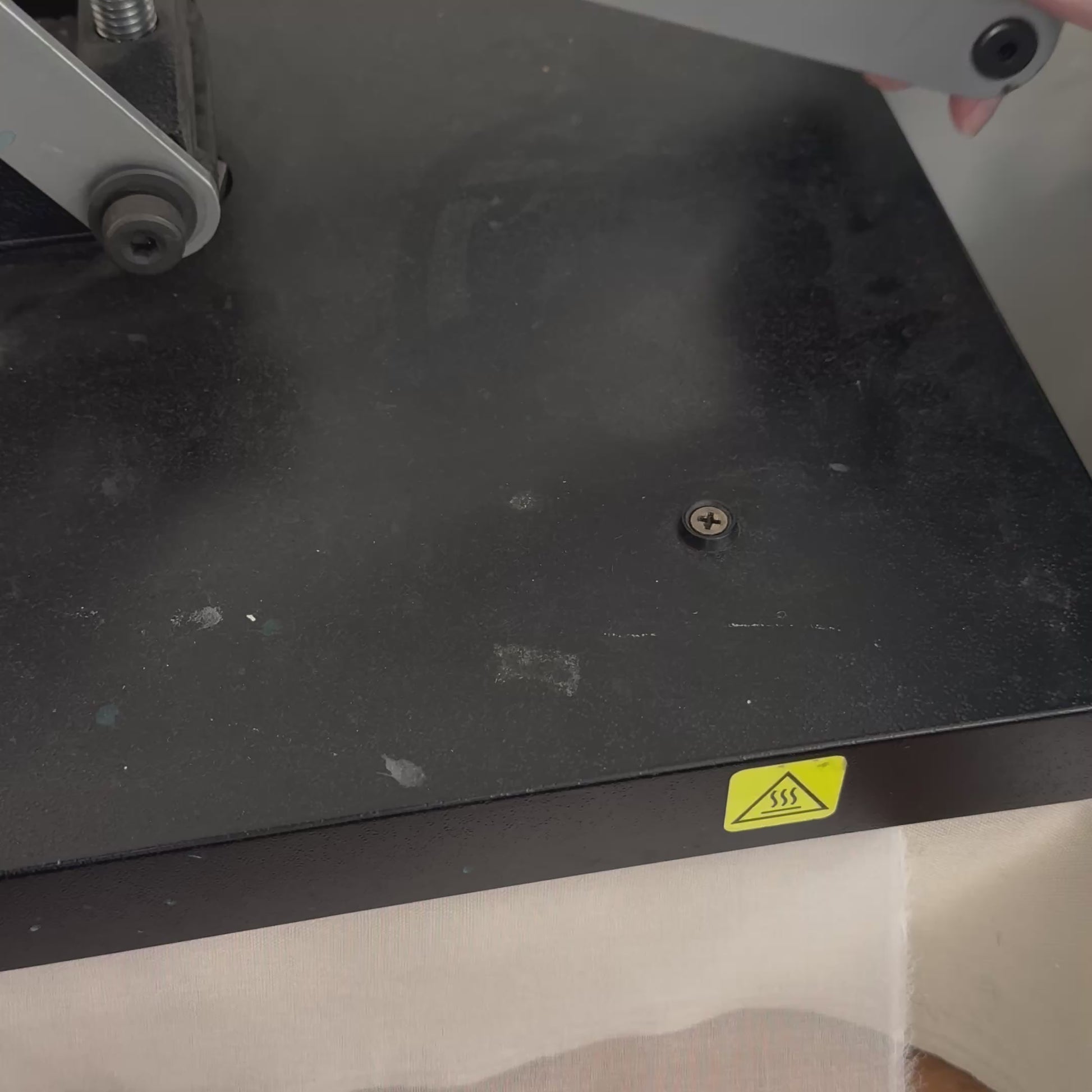 Video shows the top of an industrial heat press being opened to reveal the pressed appliqués for the cosmic patches