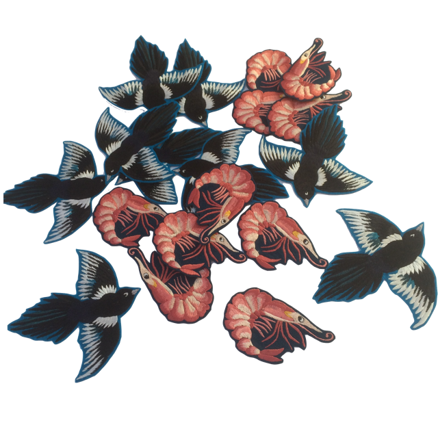 Magpie and prawn embroidered patches scattered together on white background