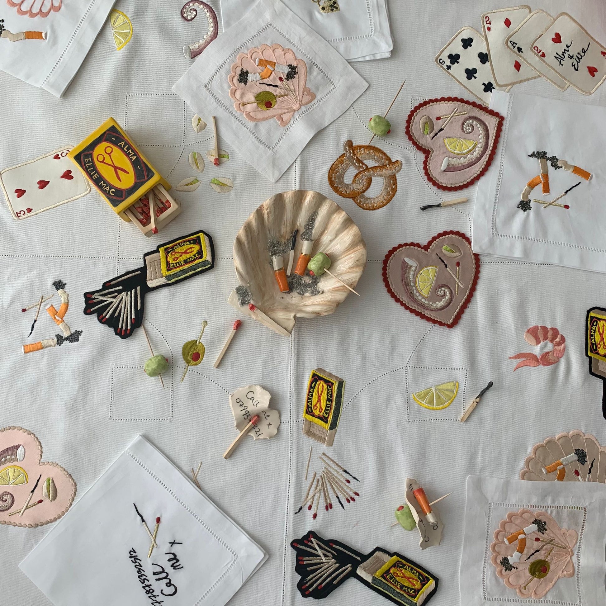 Different collaborative artworks from the Alma Berrow & Ellie Mac Embroidery collection, including embroidered artworks and napkins and ceramics