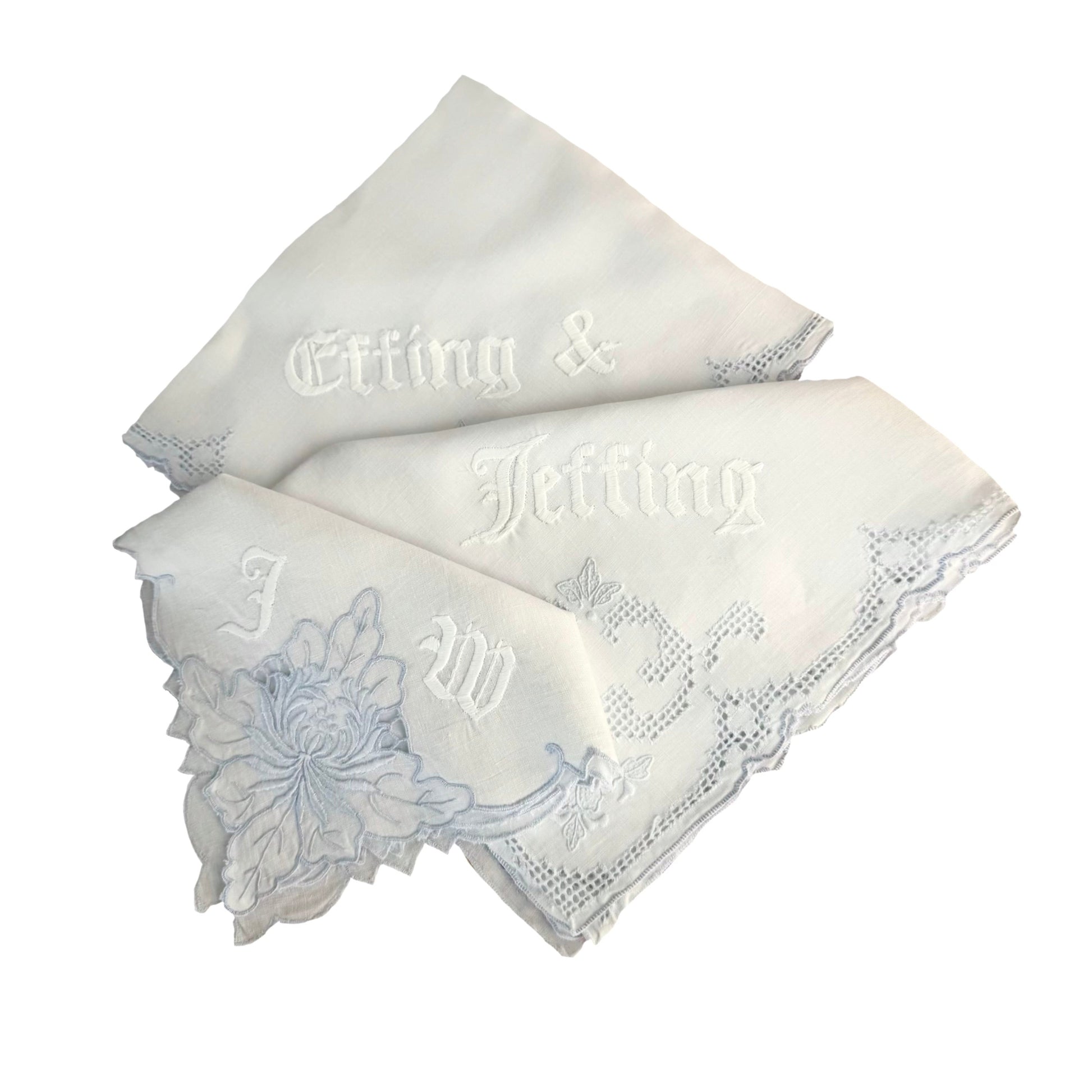 Two white handkerchiefs with embroidered text and floral design on a white background