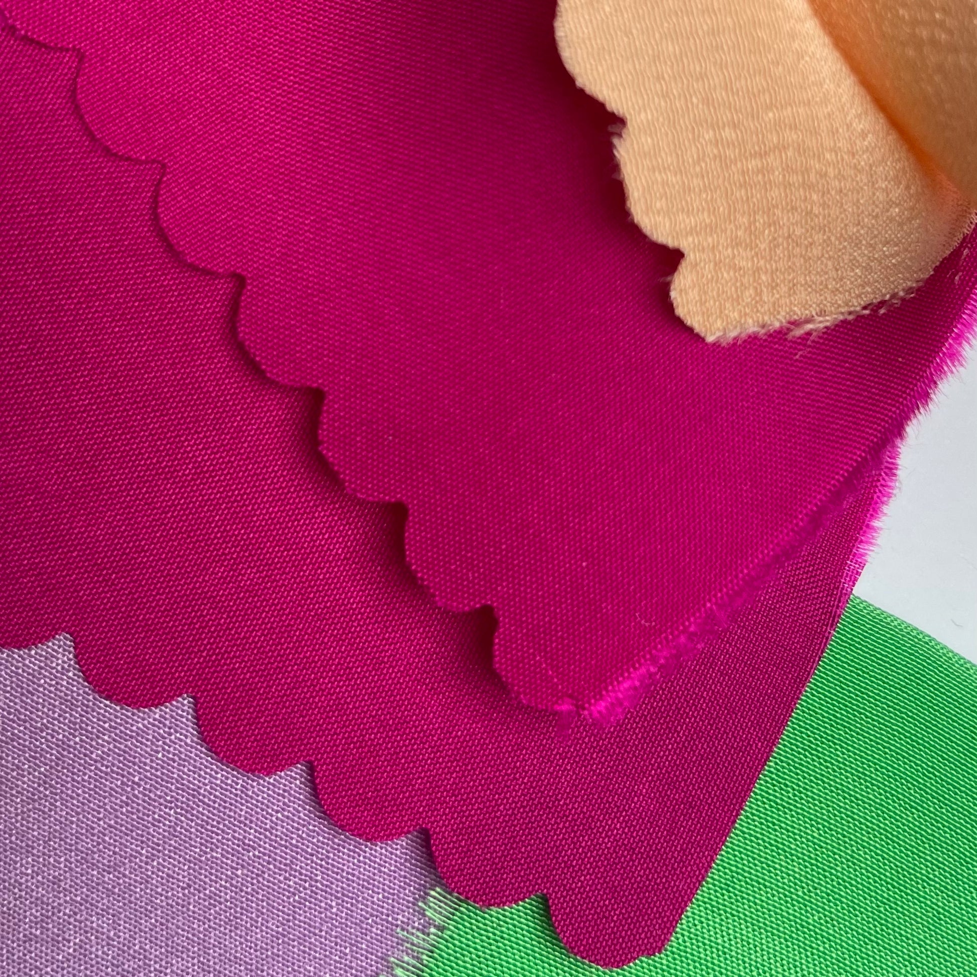 Close-up of fabrics used to make the appliques on the artwork. Green, lilac, hot pink and peach fabric can be seen
