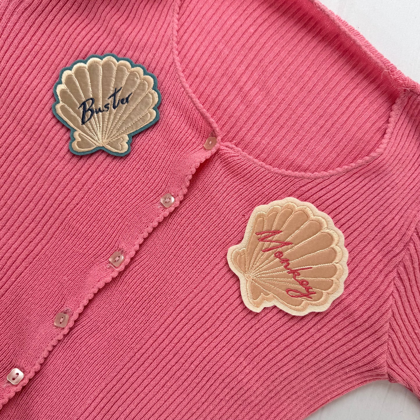 Pink ribbed cardigan with two silk applique shell patches placed on the left and right front