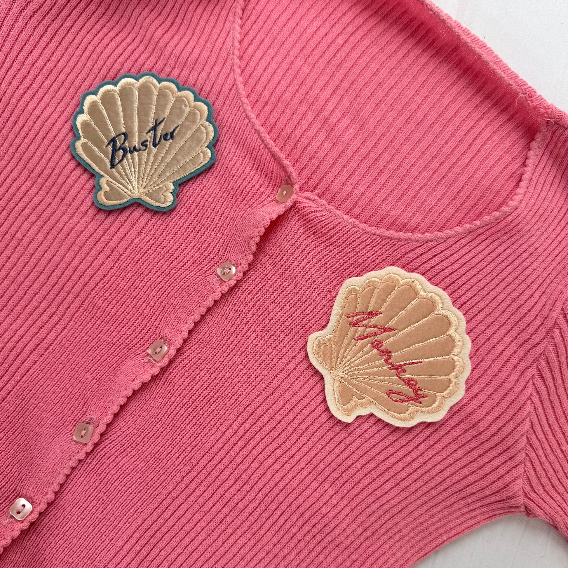 Pink ribbed cardigan with two silk applique shell patches placed on the left and right front