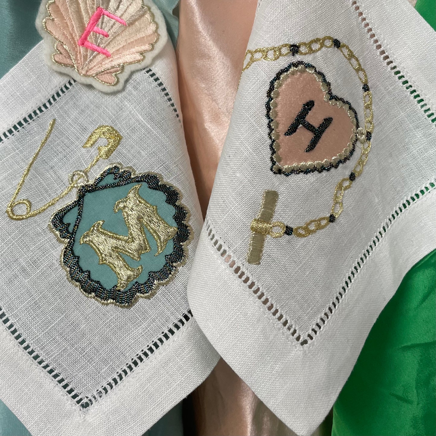 Two embroidered artworks from the Love Token collection, hanging over different colour fabrics