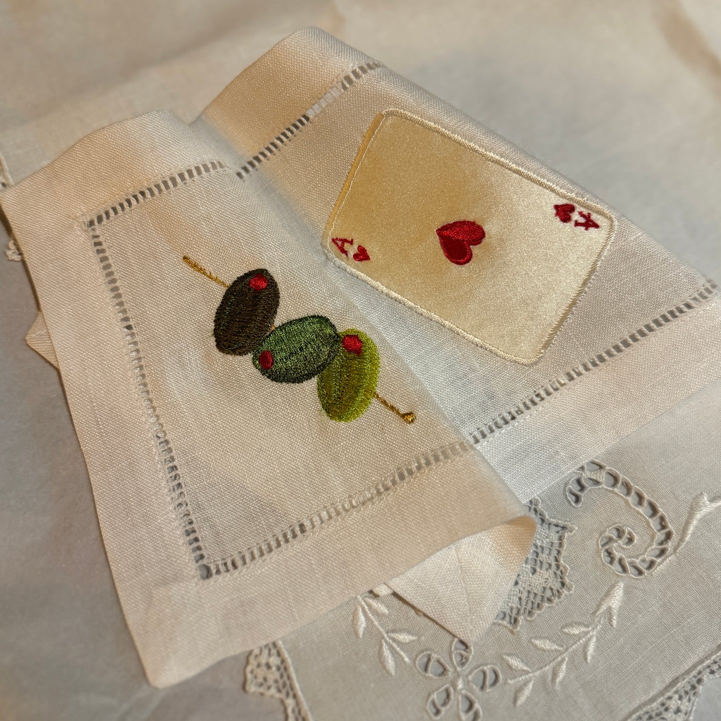 Embroidered fabric pieces with floral and heart designs on a textured surface.