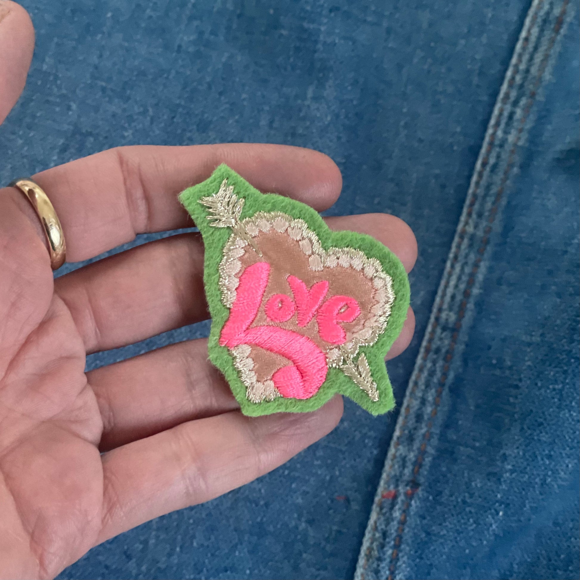 embroidered love pin on hand for scale