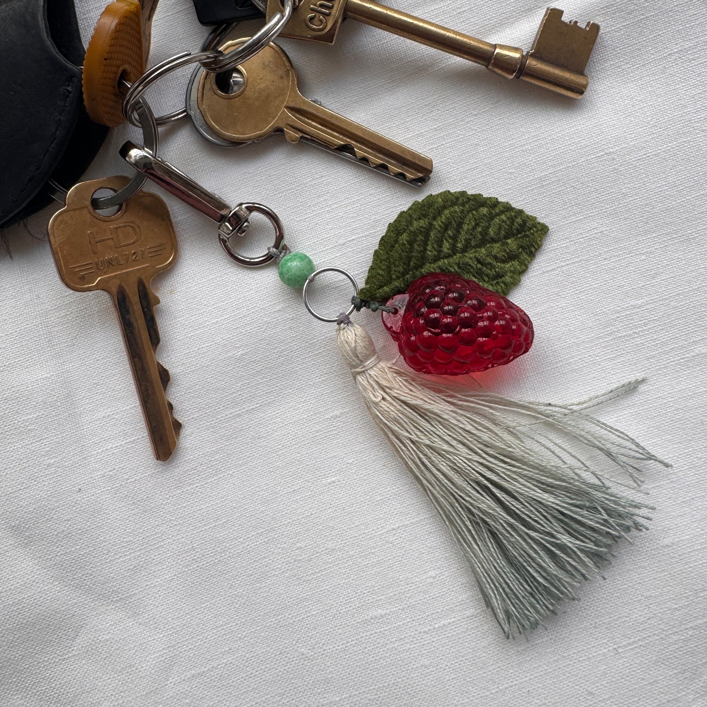 Keychain with keys and a raspberry-shaped charm on a white background