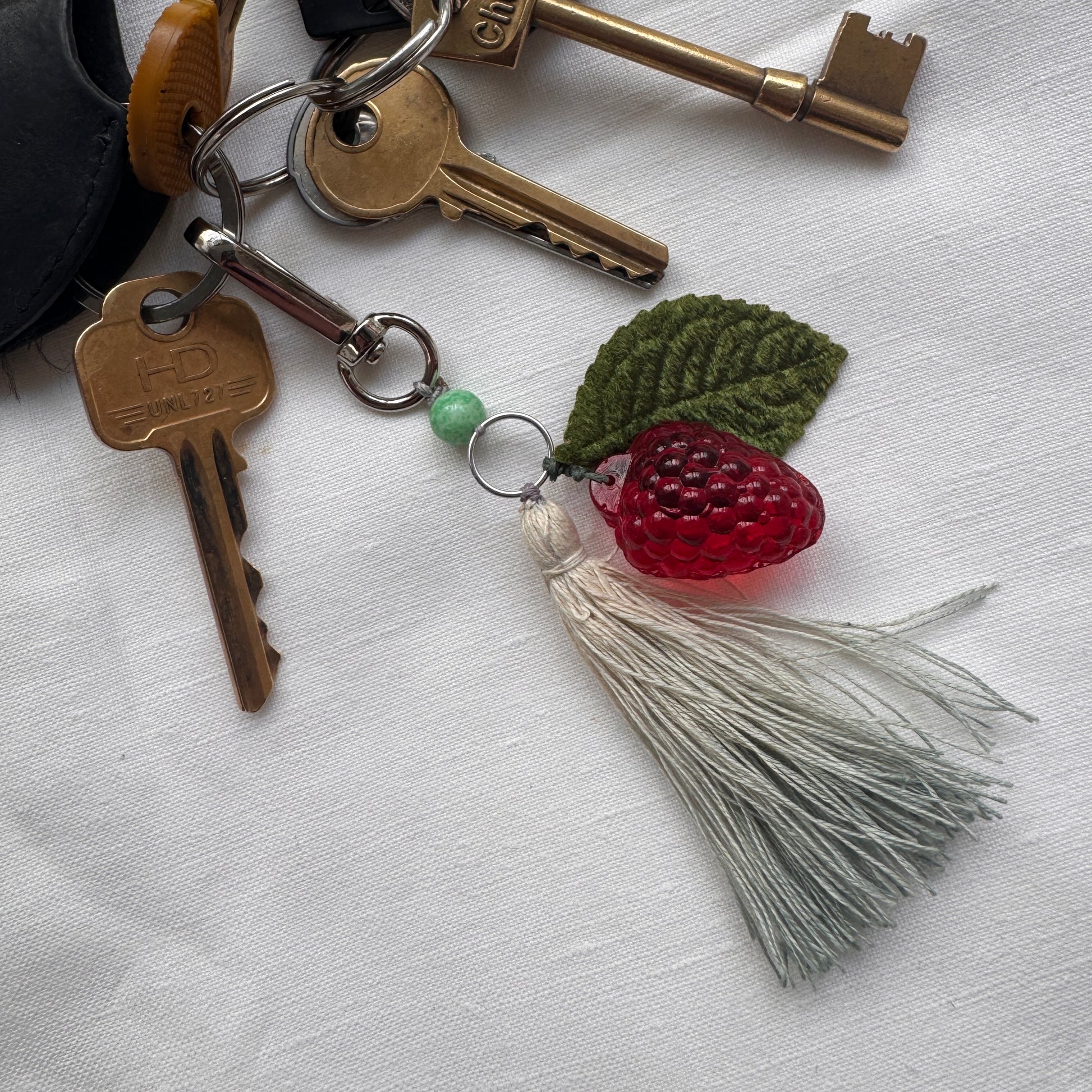 Keychain with keys and a raspberry-shaped charm on a white background