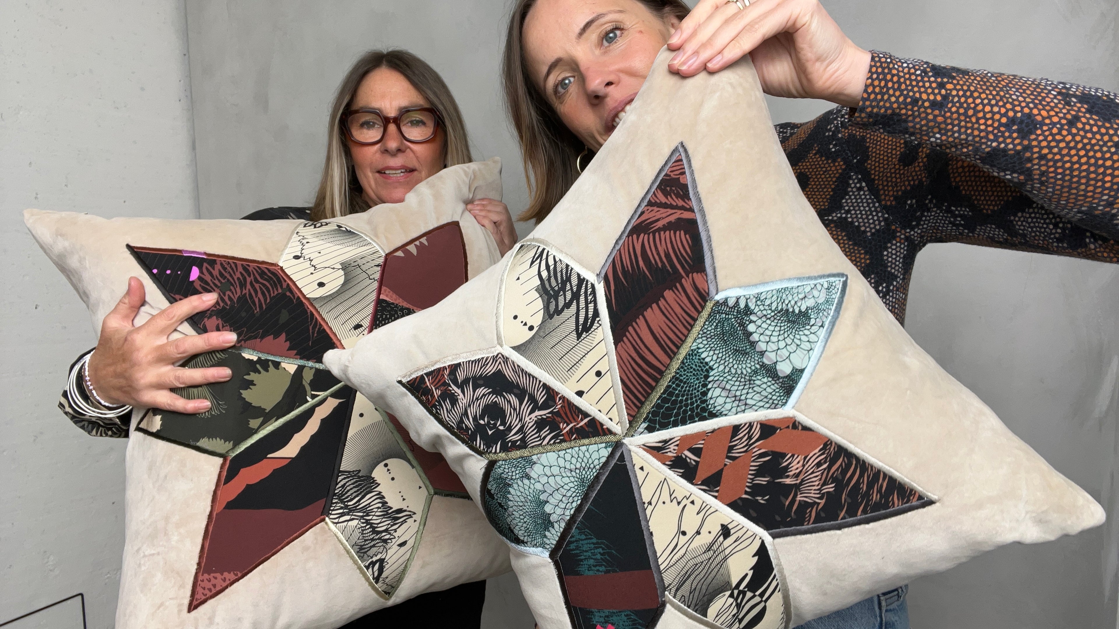 Sophie Darling & Ellie Mac holding a cushion each from their collection