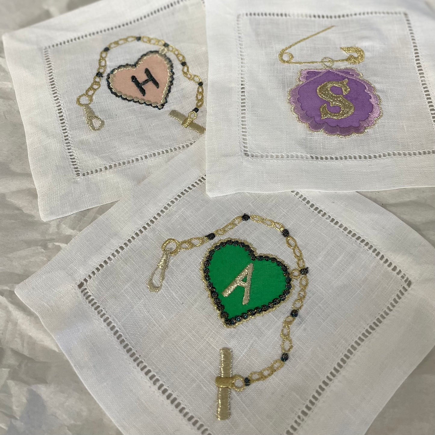 Three pieces of embroidered artworks from the Love Token collection on a white background