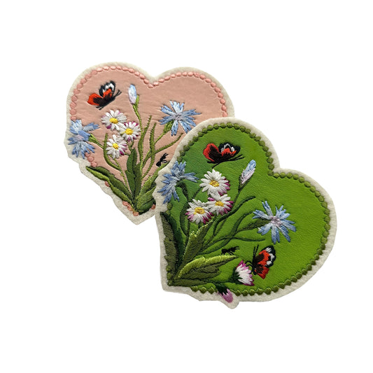 Two heart-shaped embroidered patches with flowers and butterflies on a white background.