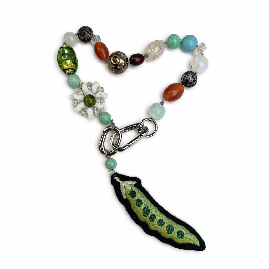 Beaded bag charm with a green pea pendant on a white background