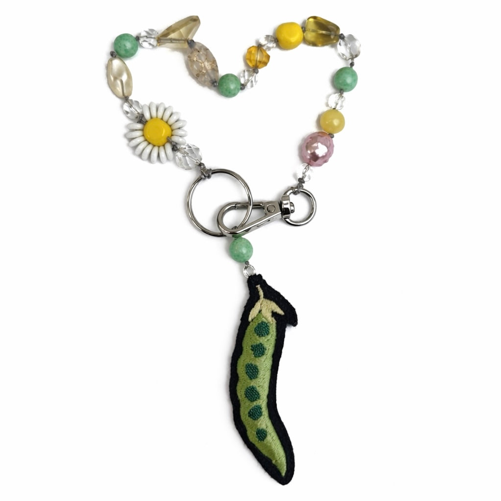 Keychain with colorful beads and pea charm on a white background