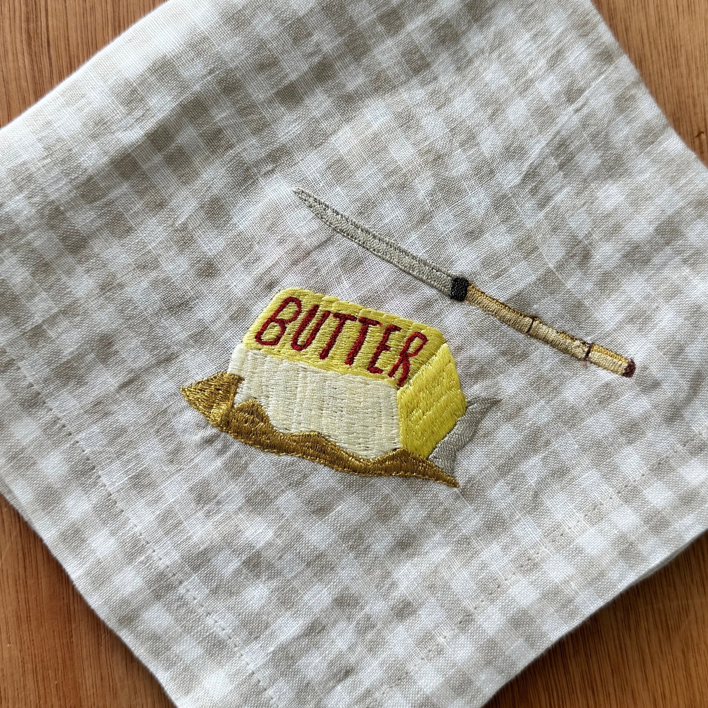 Embroidered butter block and knife on a checkered fabric background