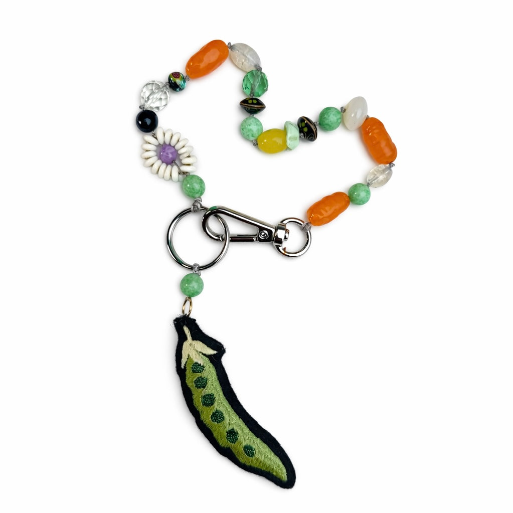 Colorful beaded keychain with a green felt pea pod charm on a white background