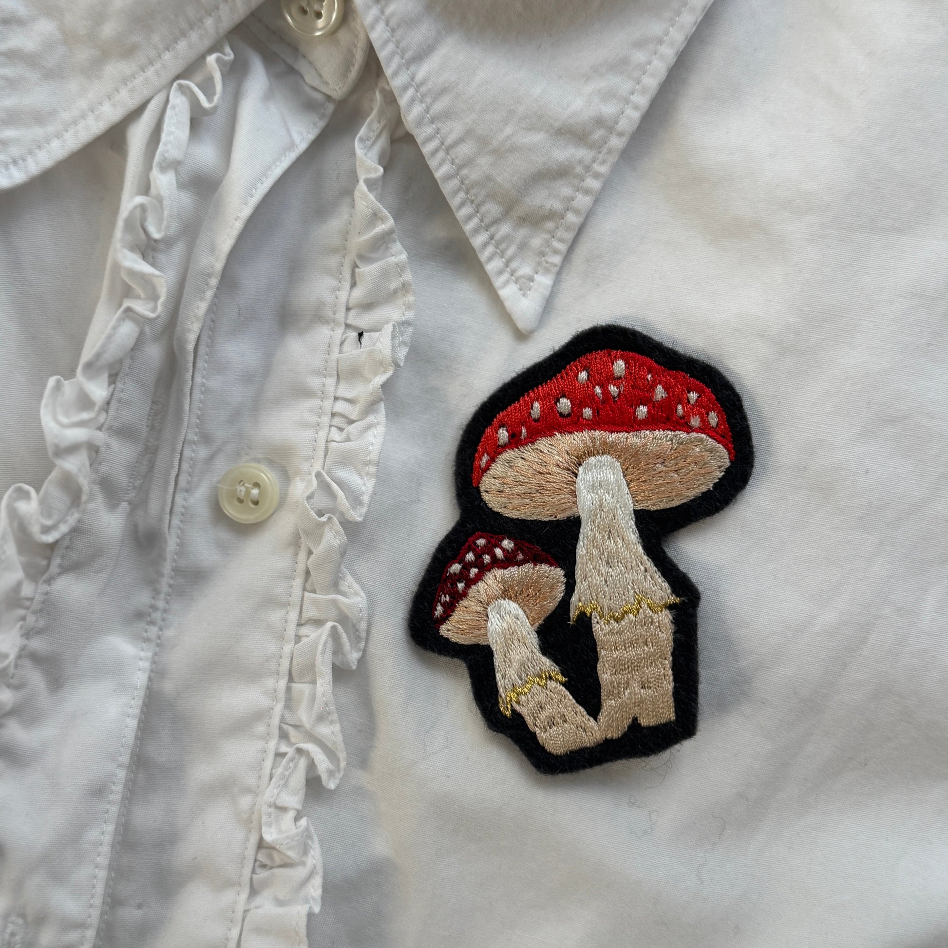 Mushroom patch on a white shirt with ruffled collar