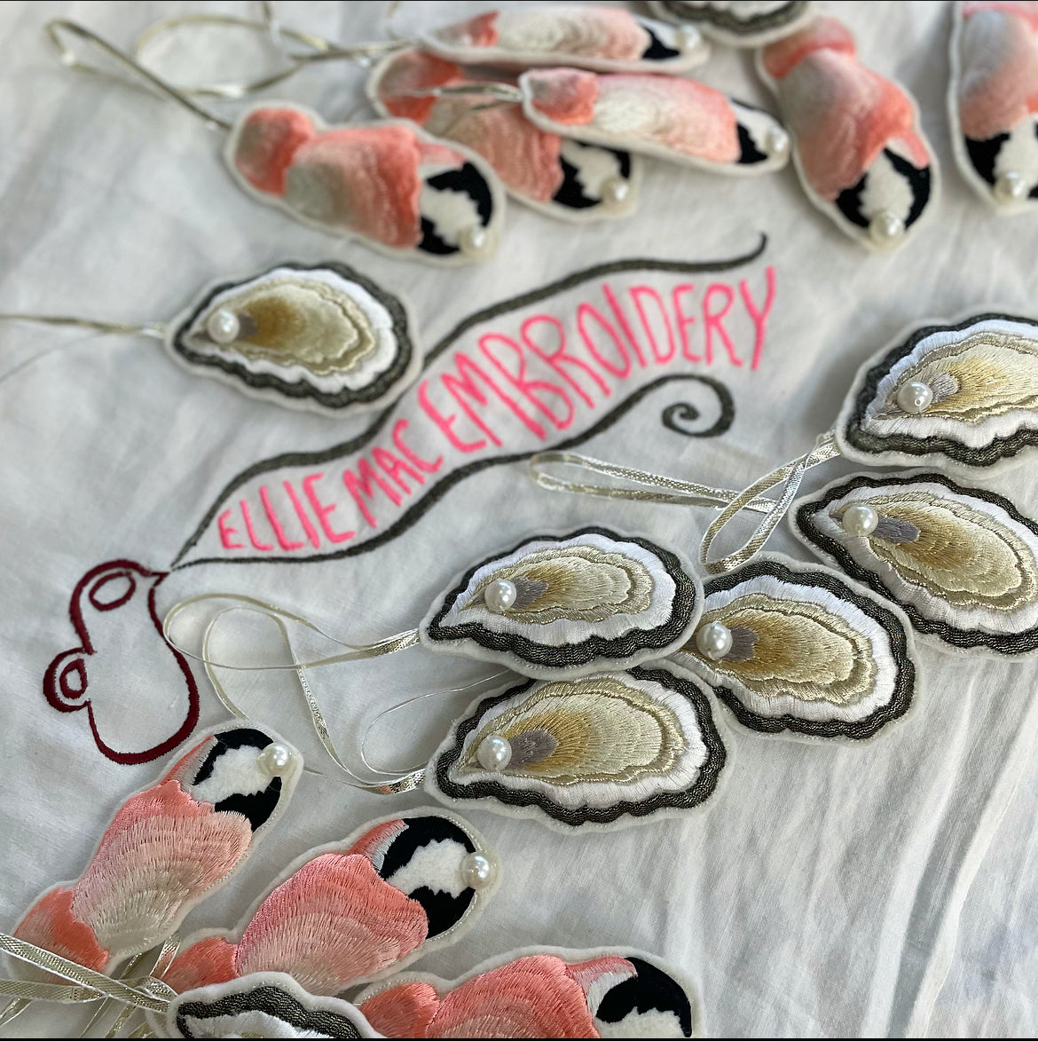 White cloth with Ellie Mac Embroidery sewn on and a selection of embroidered decorations of oysters and crab claws laid on top