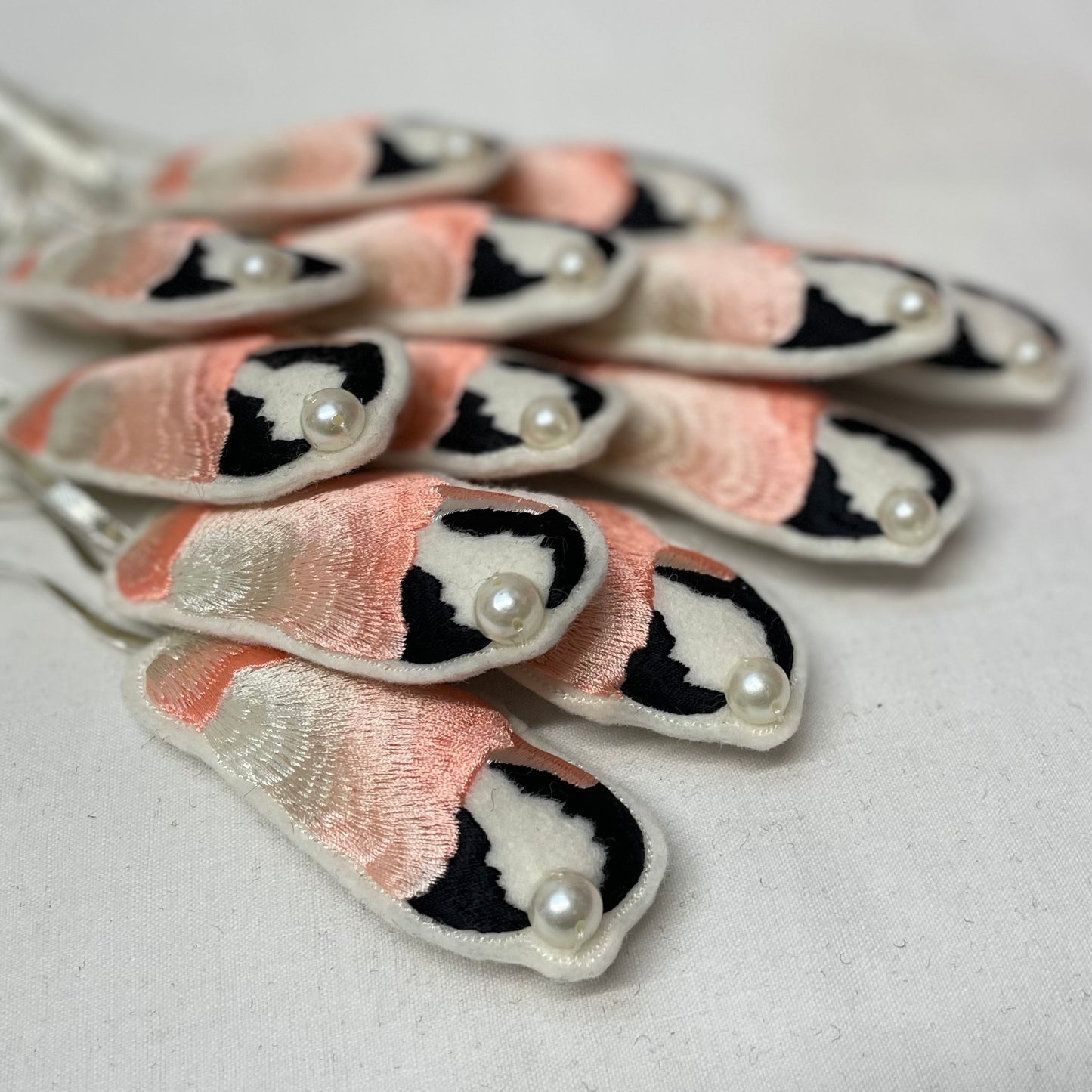 A stack of embroidered crab claws laid on top of one another, the background ones are slightly blurred with the focus on the nearest claws