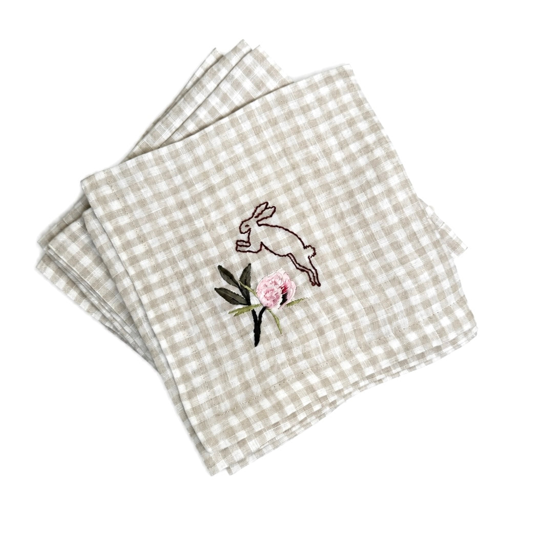 Checkered napkin with embroidered rabbit and flower design on a white background