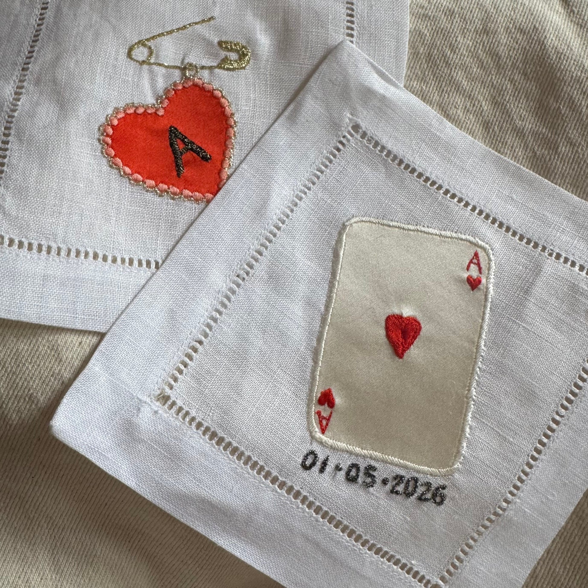 Two embroidered coasters with love heart designs and text on a beige background