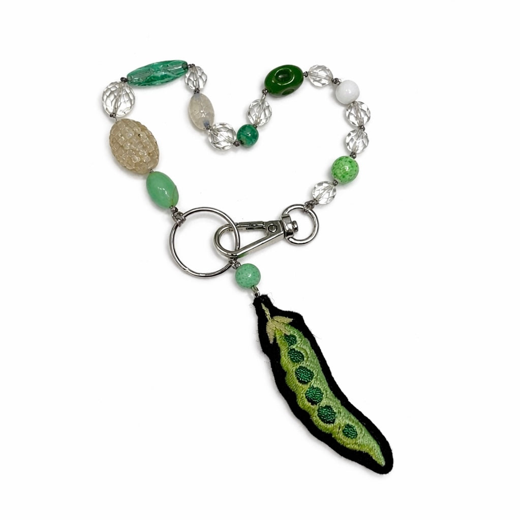 bag charm with green and white beads and a unique pea pendant on a white background