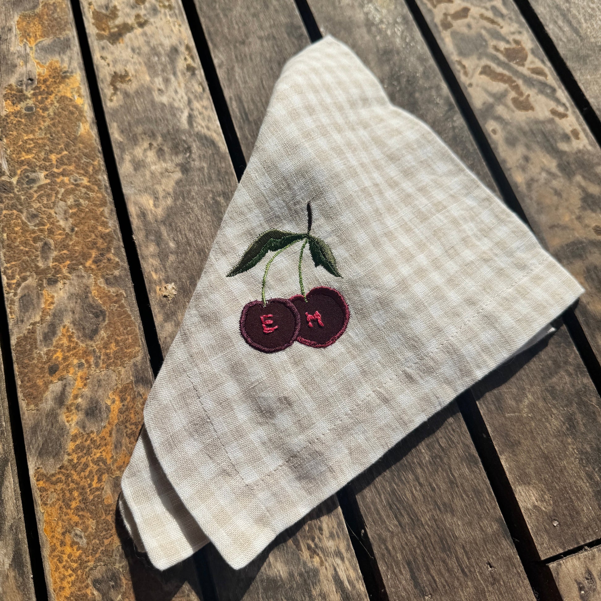 napkin with embroidered cherries on a wooden surface