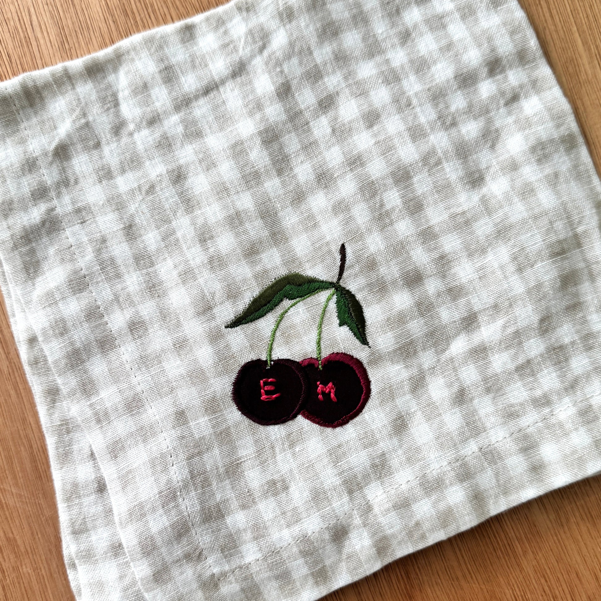 Embroidered cherries with initials on a checkered fabric