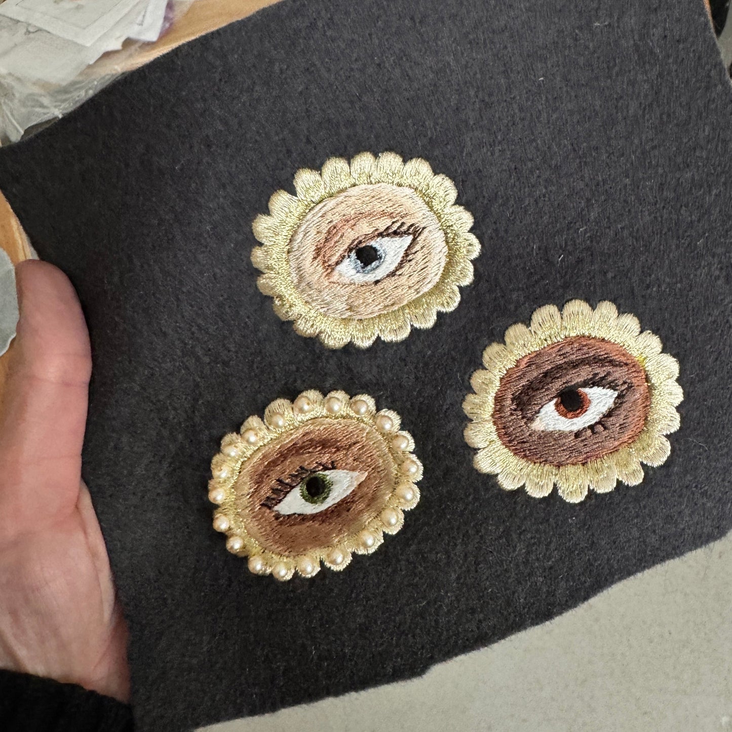 Embroidered eye designs on a dark fabric surface