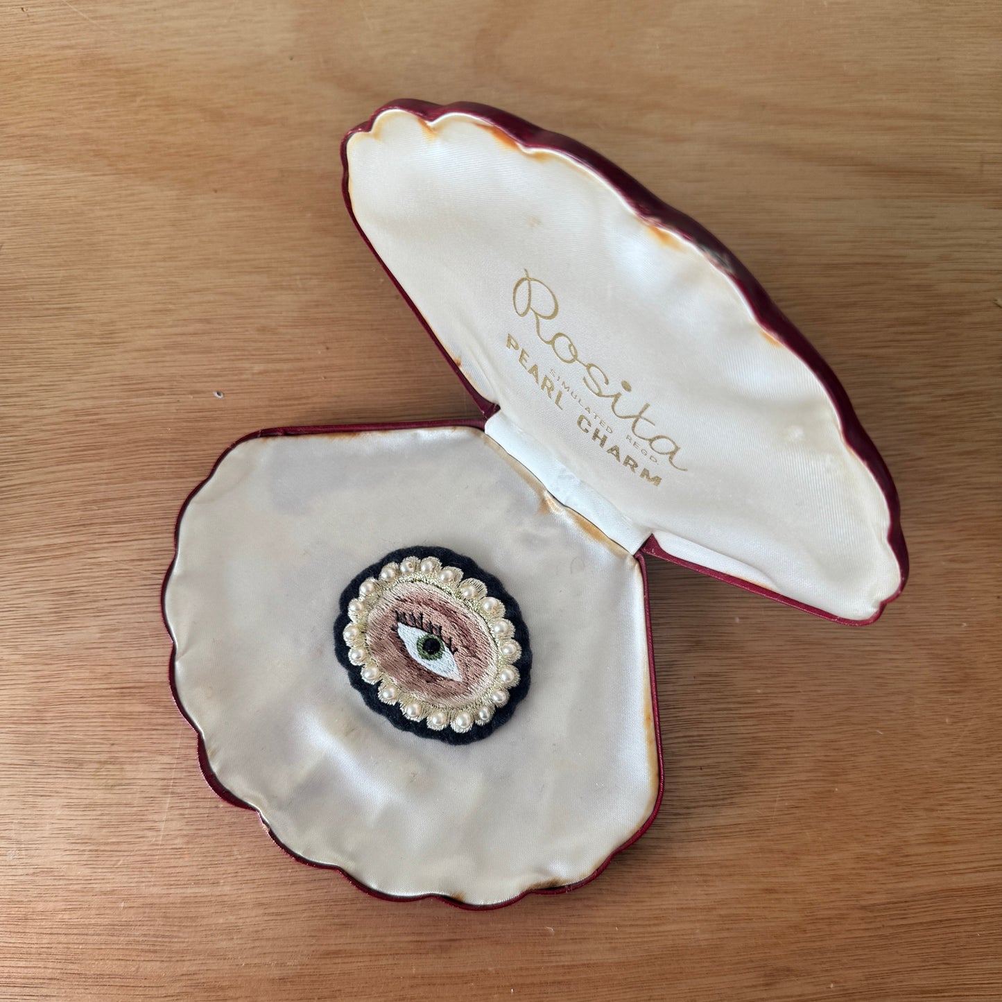 Open shell-shaped jewelry box with 'Rosita' branding on a wooden surface