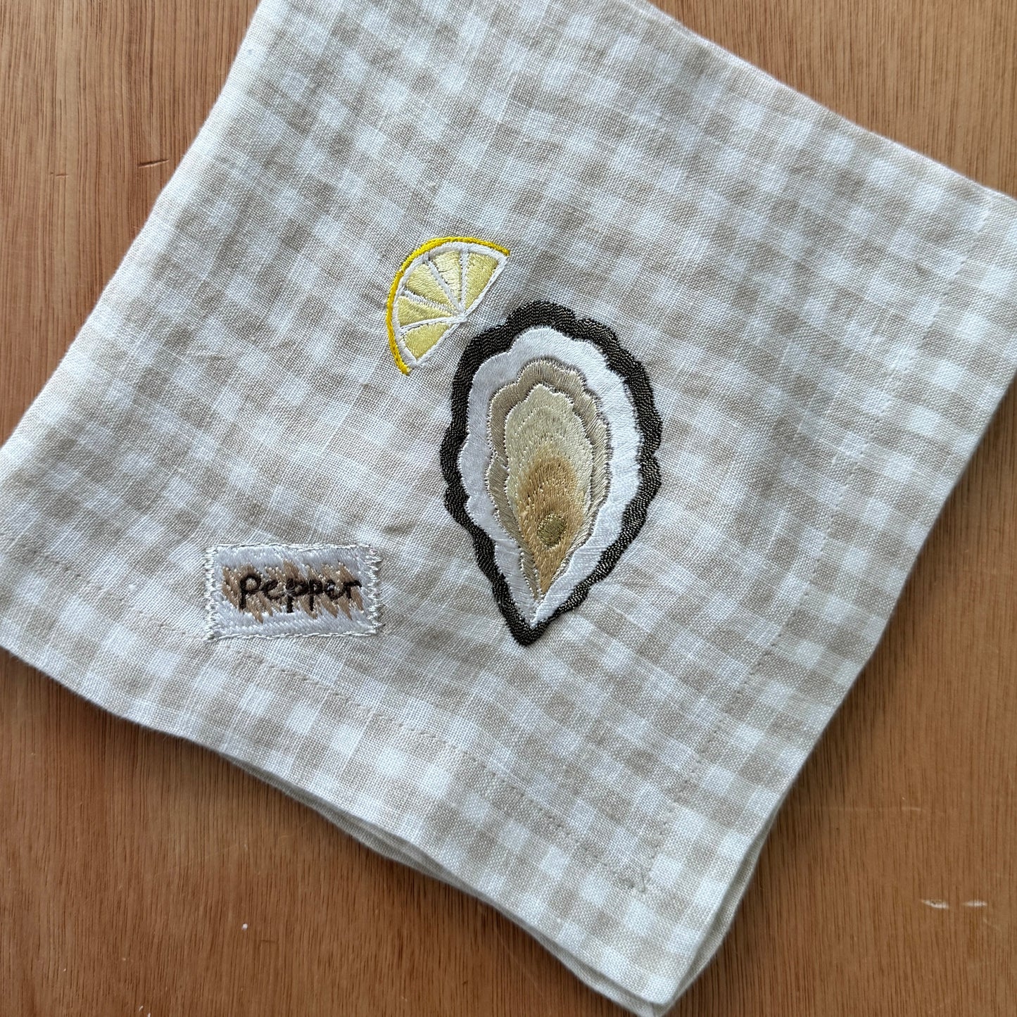 Napkin with embroidered oyster & pepper design on a checkered pattern