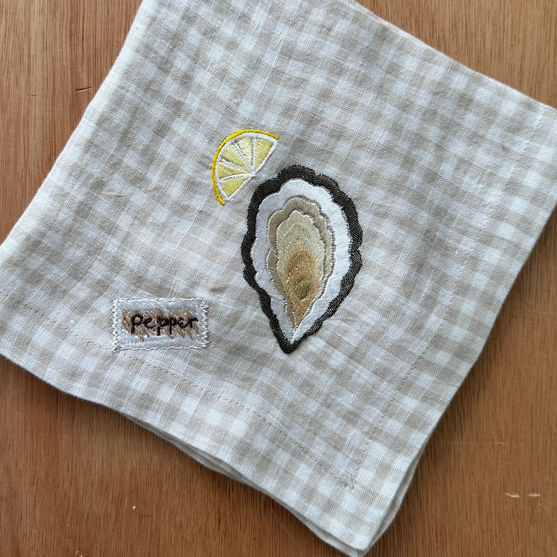 Napkin with embroidered oyster & pepper design on a checkered pattern