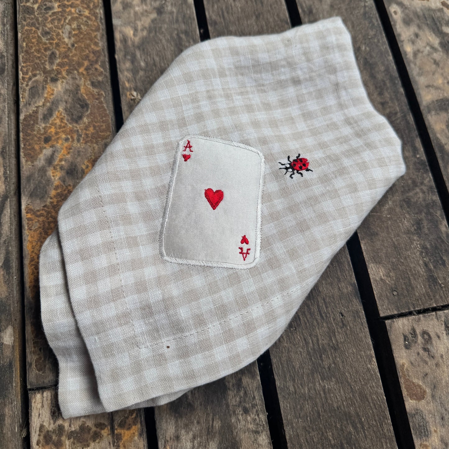 Folded checkered fabric with embroidered designs on a wooden surface