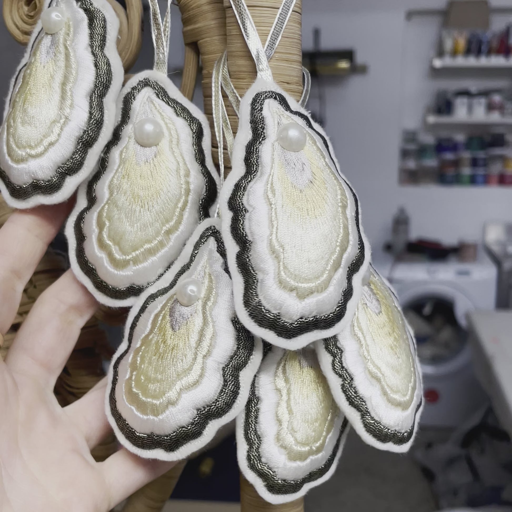 Video of a bunch of embroidered oyster decorations hanging on a rattan screen, shown close-up